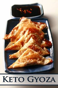 several pieces of food on a blue plate with sauce in the middle and words keto gyoza written below