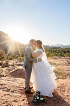 a bride and groom kissing in front of the sun on their wedding day at red rock canyon