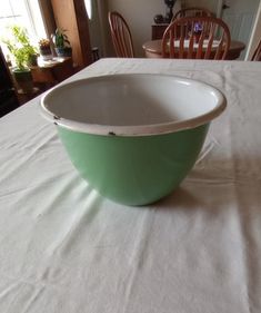 a green bowl sitting on top of a white table