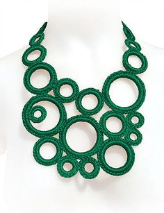 a green necklace on a mannequin with circles and spirals in the center