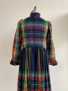 "This is a festive handmade garment from the 1960's. The dress is in a lightweight organic material in a blue plaid pattern. The neckline, bodice, and wrist are trimmed with a red cord and ruffle. The dress looks to be handmade and shows no visible flaws. The dress is semi-sheer, and a slip would be recommended. The dress is in excellent condition. Measurements: Bust: 37\" | Waist: 35\" | Hips: Free | Shoulders: 14\" | Sleeves\" 23\" | Length: 48\" Unless otherwise stated all vintage items are u Fitted Blue Plaid Cotton Dress, Retro Plaid Dresses With Ruffles, Retro Plaid Dress With Ruffles, Vintage Plaid Cotton Dress, Vintage Lined Plaid Dress, Blue Plaid Pattern, Blue Plaid Dress, Handmade Dress, Vintage Gowns