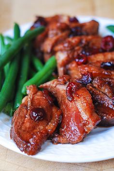 some meat and green beans on a white plate