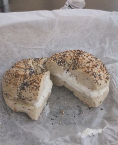 a bagel that has been cut in half and is sitting on some wax paper