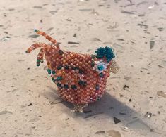 a beaded chicken sitting on top of a table