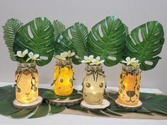 three mason jars filled with plants and animals on top of a wooden sliced table