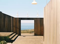 a wooden walkway leading to the beach with stairs and lights on each side, in front of an ocean view