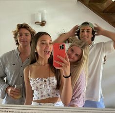 three people taking a selfie in front of a mirror with one person holding a cell phone