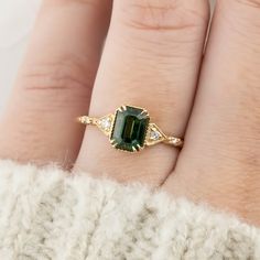 a woman's hand with a gold ring and green tourmaline stone on it