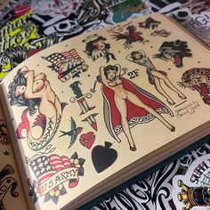 an open book with tattoos on it sitting on top of a bed covered in stickers