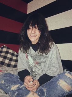 a woman sitting on top of a bed next to a black and white striped wall