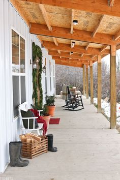 a porch covered in snow with rocking chairs and christmas decorations