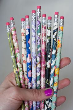 a person holding a bunch of pens in their hand with flowers all over the top