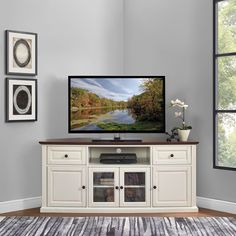 a flat screen tv sitting on top of a white entertainment center next to a window