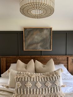 a bed with pillows and blankets on top of it next to a painting hanging above the headboard