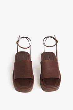 The Frances Sandal is what VB herself calls an 'exaggerated hotel pool slide' ‚Äì a flat, chunky sandal with a sole made from leather and EVA to create different layers and textures. The squared toe shape and cross-over minimalist leather band with waxed, raw edges channel the laidback aesthetic of the 90s, while a stitched, slightly padded in-sock and adjustable ankle strap that's hand-stitched to the cross-over band provide comfort and practicality. The Dark Brown hue is the perfect complement Flat Sandals Aesthetic, Brown Leather Platform Sandals, Old Money Sandals, 2024 Sandals, Laidback Aesthetic, Brown Slides, Pool Slide, Natural Palette, Hotel Pool