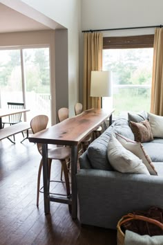 a living room filled with furniture and a wooden table in front of a large window