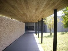 an empty walkway in front of a building with wood panels on the walls and grass