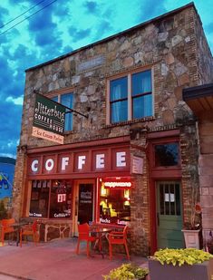 the outside of a coffee shop with tables and chairs