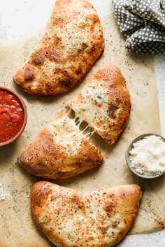 three pieces of pizza sitting on top of a cutting board next to some sauces