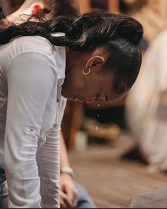 a woman sitting on the ground with her head in her hands while looking down at something