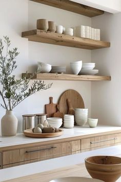 a kitchen with wooden shelves and white dishes on top of it, along with bowls