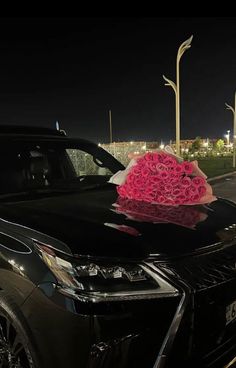 a black car with pink flowers on the hood parked in front of a street light