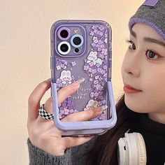 a woman holding up her phone case in front of her face and wearing headphones