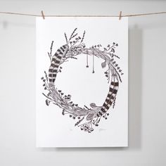 a card hanging on a clothes line that has a wreath drawn in the middle with black and white stripes