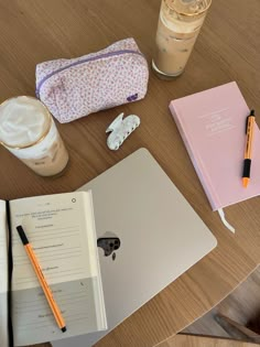 an open notebook sitting on top of a wooden table next to a cup of coffee