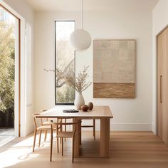 a dining room table and chairs in front of a large window with an art piece on the wall