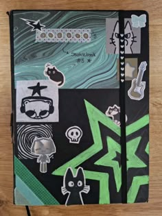 an open notebook with drawings and stickers on the cover, sitting on a wooden surface