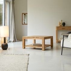 a living room filled with furniture and a white rug on the floor next to a window