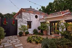 an outdoor patio with potted plants and lights strung from the roof, along with small trees