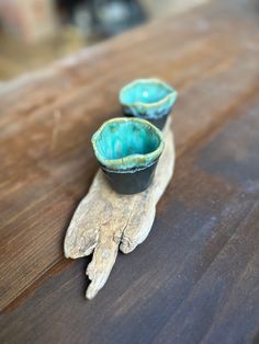 two small blue bowls sitting on top of a wooden table next to a piece of driftwood