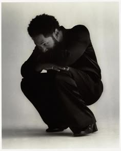 a black and white photo of a man crouching down with his hands on his knees