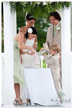 a couple and their son are getting ready to cut the cake at this outdoor wedding