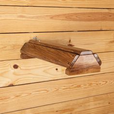 a wooden object is hanging on the side of a wood paneled wall with nails in it