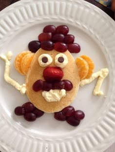 a white plate topped with pancakes covered in fruit and veggie art on top of it