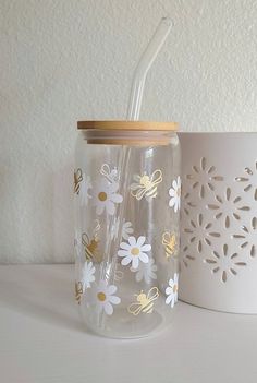 a glass with a straw in it sitting next to a white cup on a table