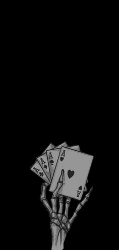 a hand holding playing cards in the dark