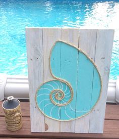 a wooden sign with a sea shell painted on it next to a pool and deck