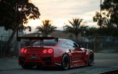 a red sports car is parked on the side of the road with its lights on