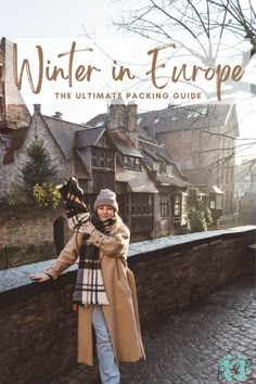 a woman standing next to a brick wall with the words winter in europe on it