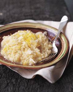 a brown and white plate topped with mashed potatoes next to a fork on top of a napkin