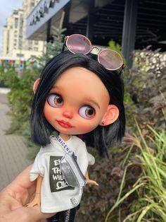 a close up of a person holding a doll with sunglasses on it's head