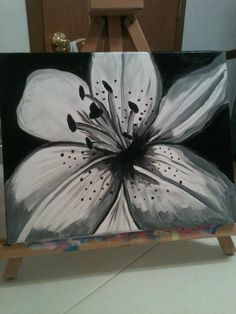 a black and white flower painted on an easel