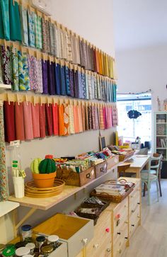 a room filled with lots of different types of fabrics on the wall and shelves next to each other