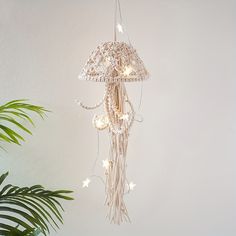 a white chandelier hanging from the ceiling next to a potted palm tree