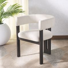 a white chair sitting next to a potted plant on top of a carpeted floor