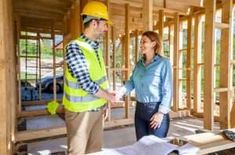 a man and woman standing in front of a house under construction